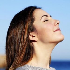 Close-up of a woman’s face with eyes closed, relaxing in a calm and serene environment.