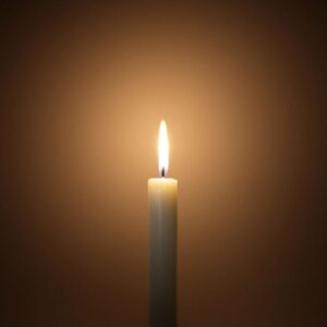 Lit candle glowing in the dark, symbolizing a bright and open mind