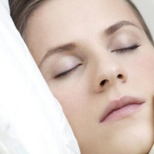 Woman sleeping deeply, resting peacefully in a calm and darkened room.