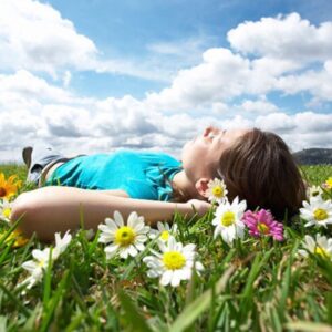 Person lying on green grass in a relaxed position, symbolizing peace, calm, and connection with nature.