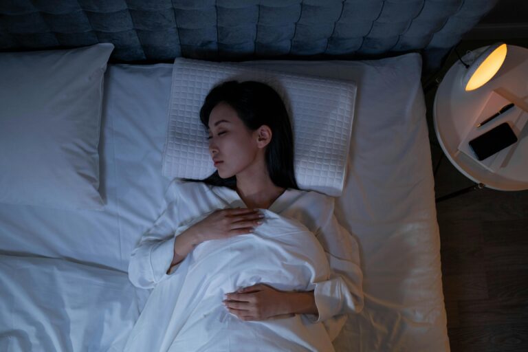 A person lying peacefully in bed under soft moonlight, surrounded by gentle glowing waves of calm energy symbolizing hypnosis guiding them into sleep.