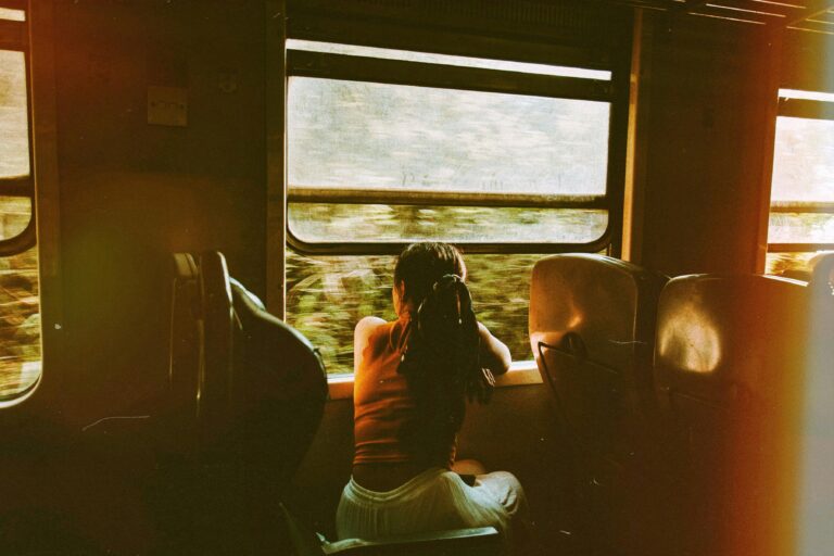 A woman sitting by the window of a smoky train ride, symbolizing reflection, journey, and emotional release.