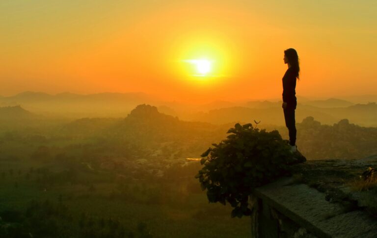 A person standing tall on a quiet hilltop at sunrise, bathed in golden light, symbolizing new confidence and strength.
