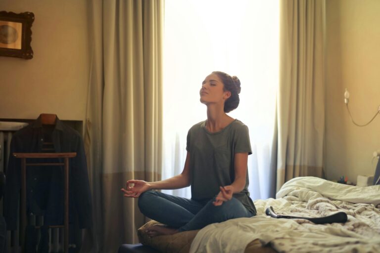 Woman meditating indoors, bathed in sunlight, representing calm and relaxation for 'Be Calm in Six Minutes' session.