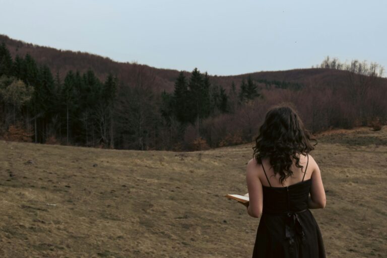 Woman journaling in front of a beautiful forest, reflecting peacefully and connecting with nature.