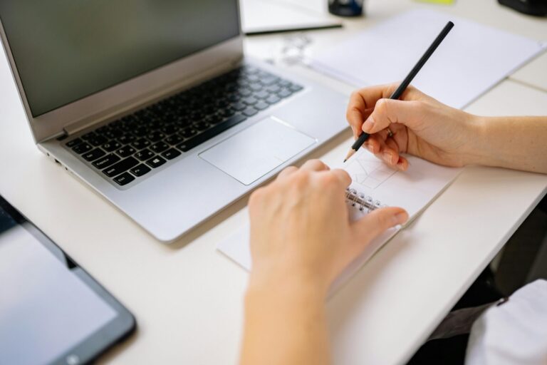 Person sitting in front of a computer, writing attentively as part of memory improvement practice.