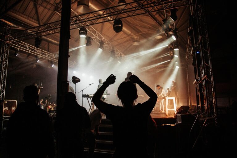 A singer or musician standing backstage with eyes closed, taking a deep breath to release tension and focus before performing on stage.