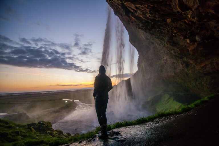 A person standing peacefully near a gentle waterfall with mist in the air, symbolizing clarity, calm, and connection with nature.