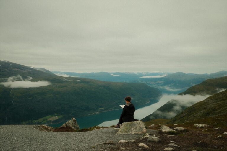 A man meditating on a mountain peak, symbolizing mindfulness, spiritual growth, and inner peace in nature