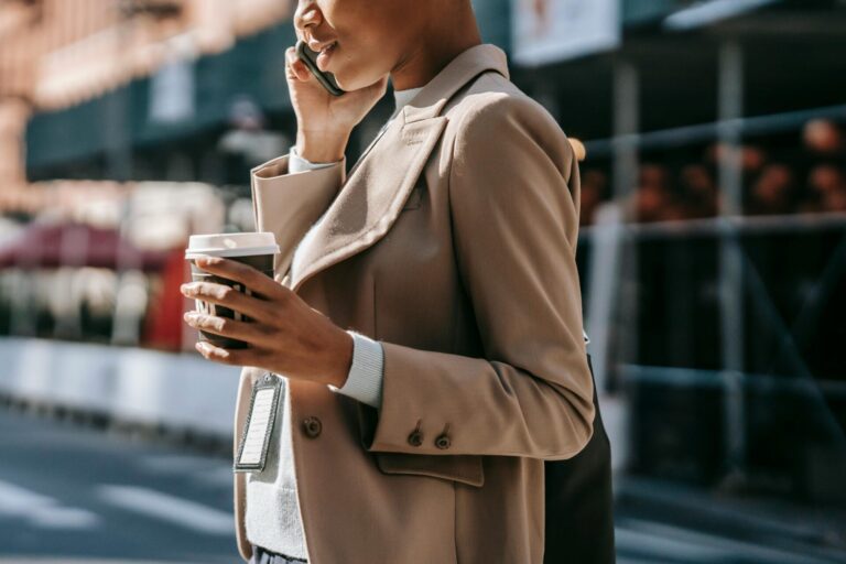 Woman standing with a cup of coffee, calmly talking to someone, showing confidence in handling conflict.