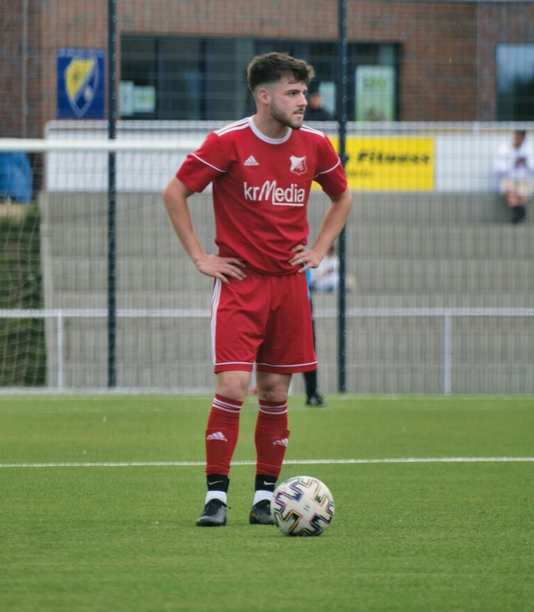 A football player standing over a penalty spot, preparing to take a focused and confident shot.