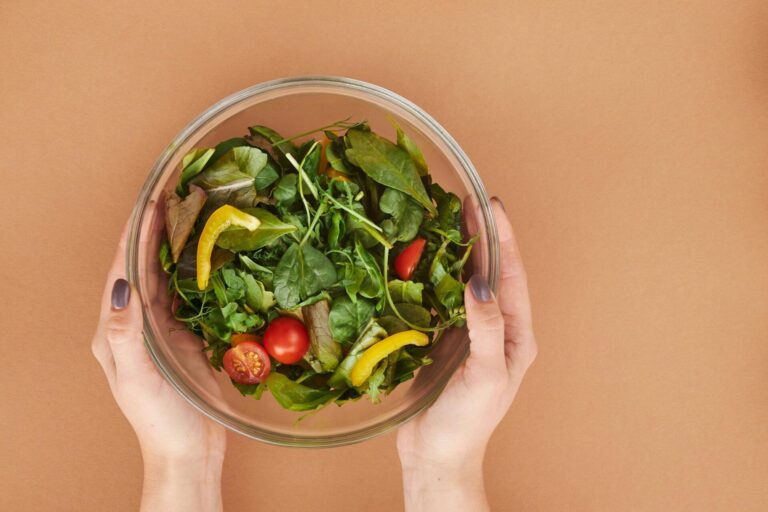 Person happily eating a fresh salad, full of vegetables and greens for a healthy lifestyle
