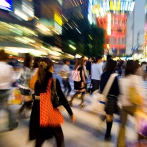 A group of people crossing a city street at night with blurred lights and motion.