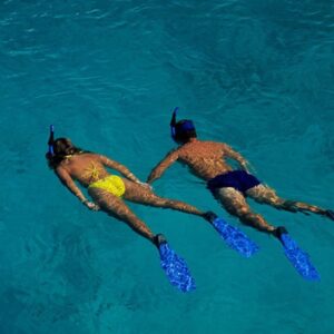 A man and woman snorkeling together in clear blue water.