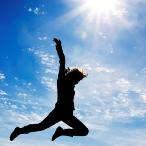 A person standing with open arms against a bright sky, symbolizing freedom from limiting beliefs.