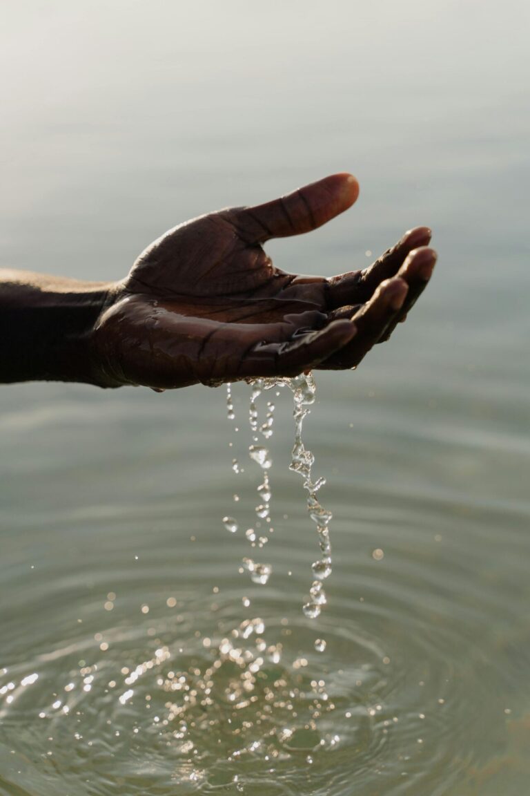 Hands gently letting sand or water slip through, symbolizing release and letting go.