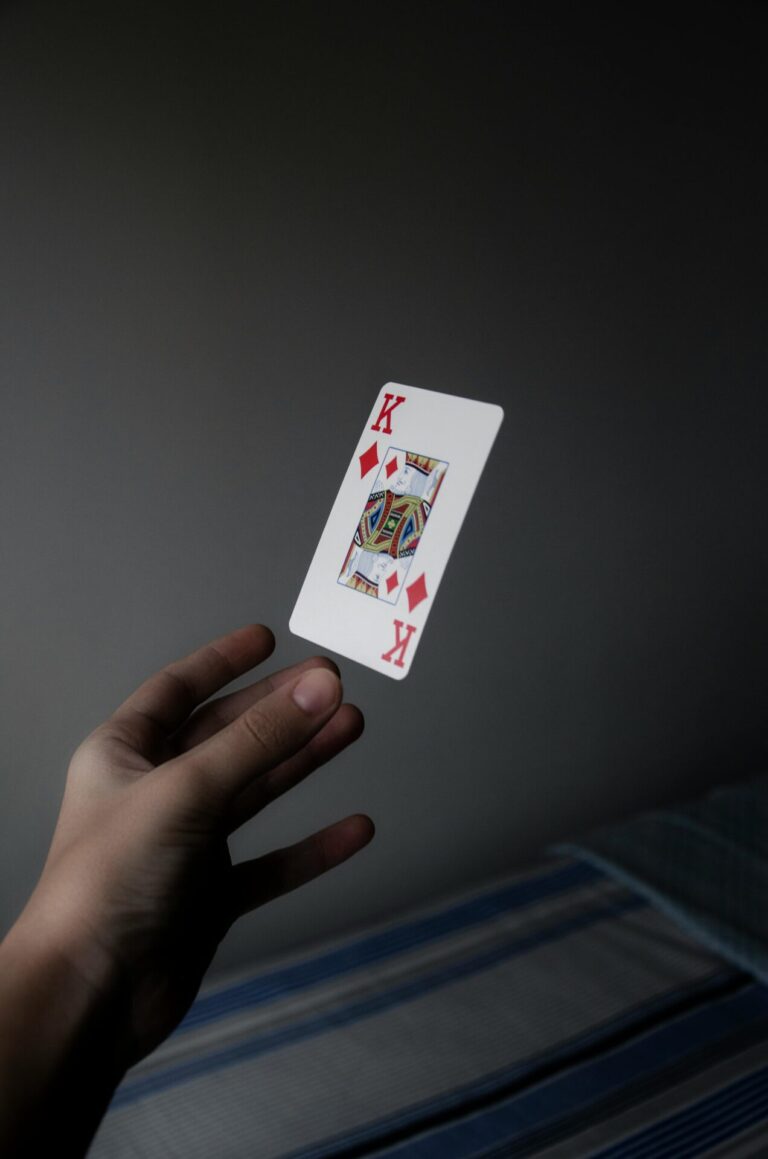Hand holding a King of Diamonds playing card against a dark background