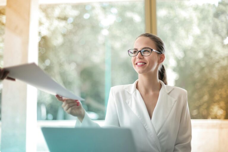A woman holding paper documents confidently, with a calm and assured expression.