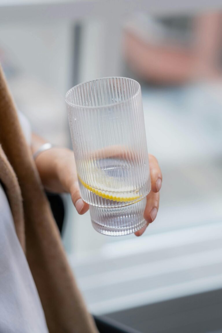 A person calmly holding a glass of water, appearing relaxed and mindful.