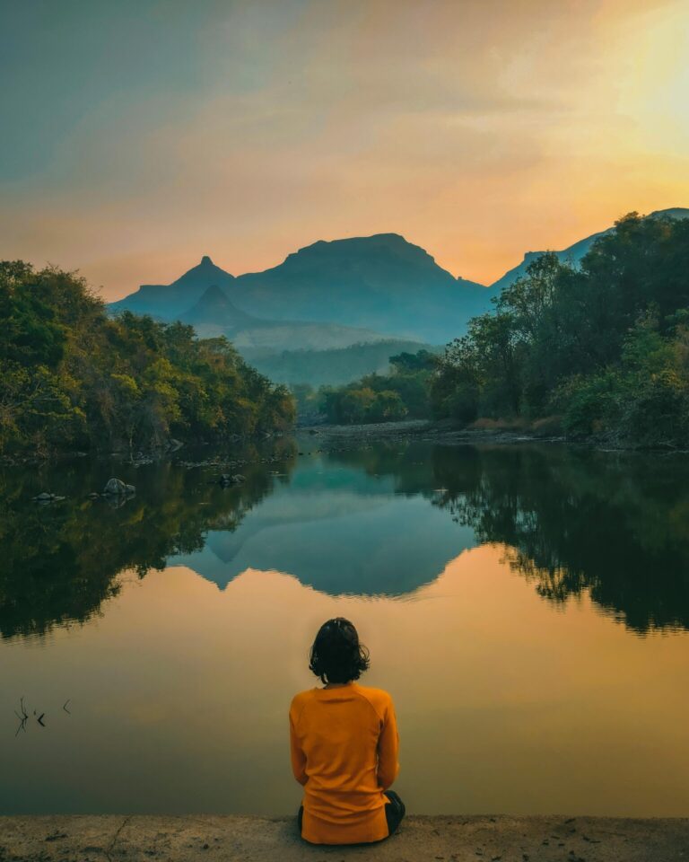 A person meditating in a sunlit forest, surrounded by trees and soft natural light.