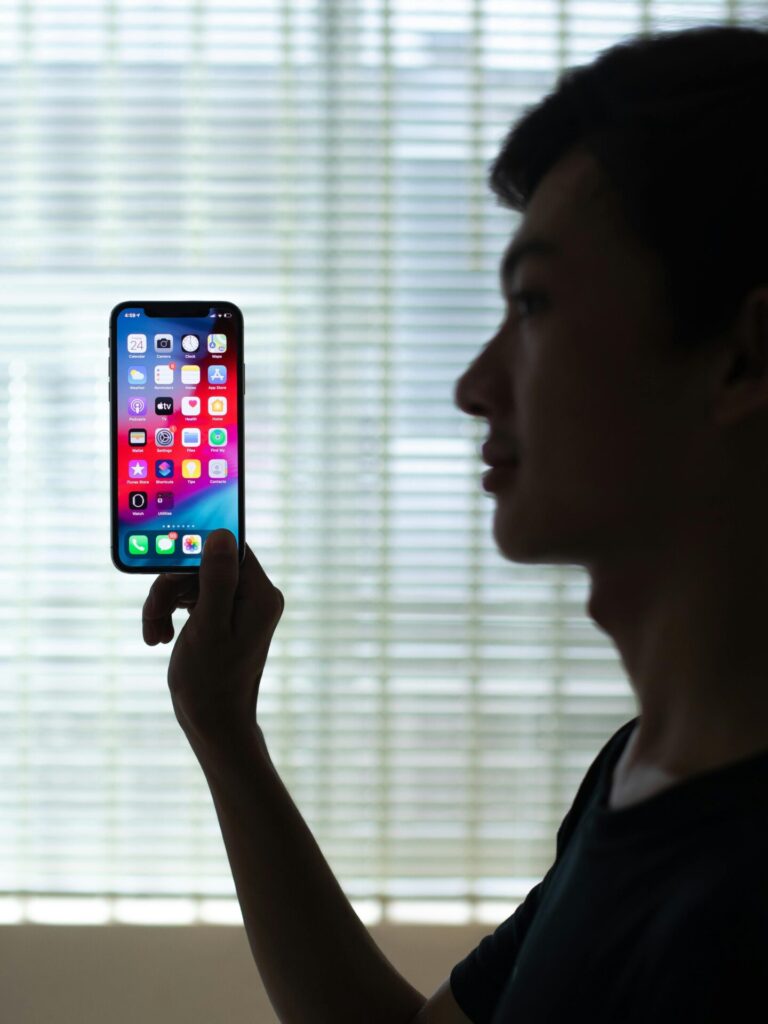 Person holding a smartphone, viewed from the front, focused on the screen.