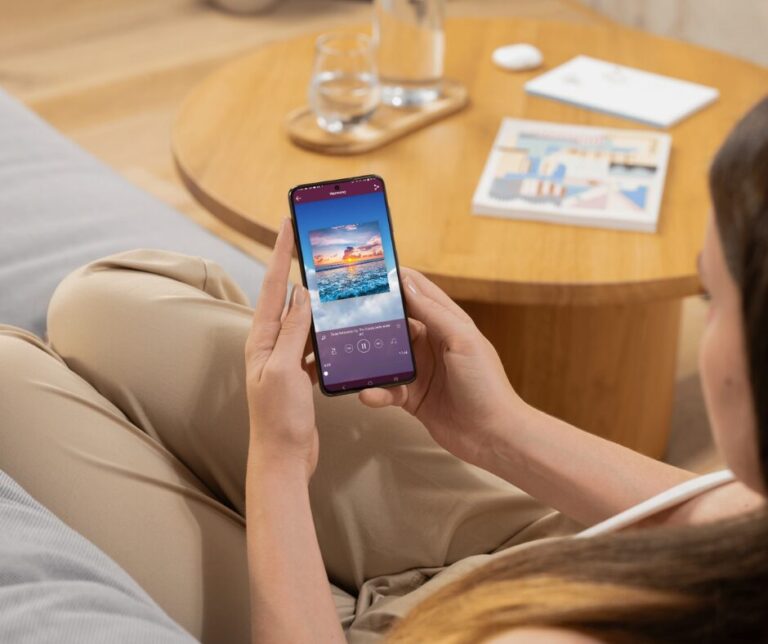 Woman holding a phone, using the Harmony Hypnosis app for deep relaxation with an ocean meditation session