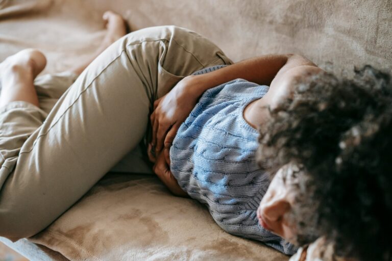 Tired person sitting down holding their body in discomfort from chronic pain