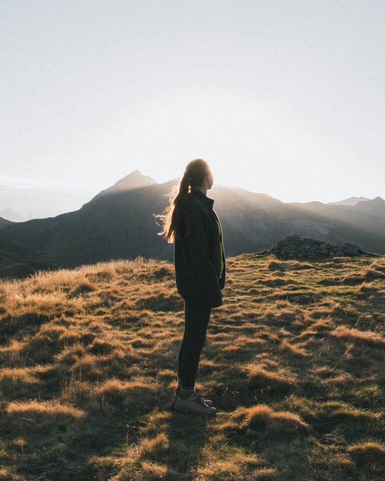 Woman standing in mountains during sunrise enjoying peaceful view