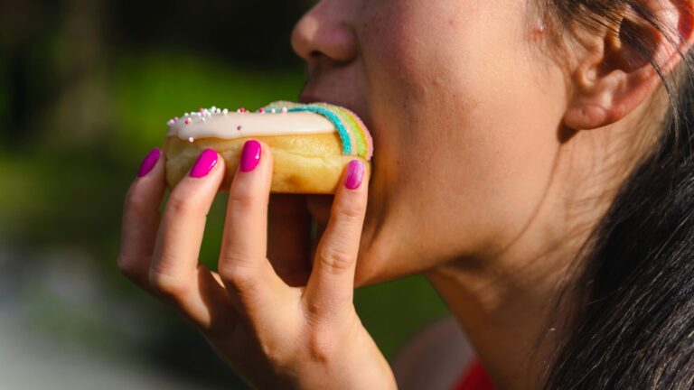 Person eating donuts to satisfy sugar cravings in a casual setting
