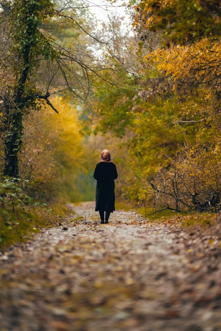 Person standing peacefully in a forest surrounded by trees