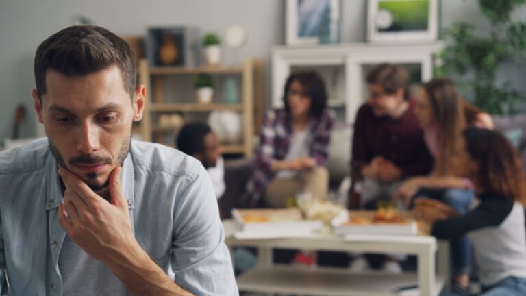 Person in a small social setting looking hesitant during conversation