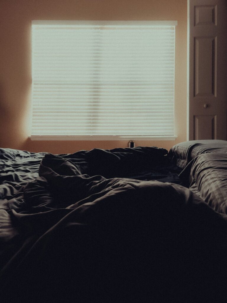 Person relaxing comfortably on a bed or cozy couch beside a window