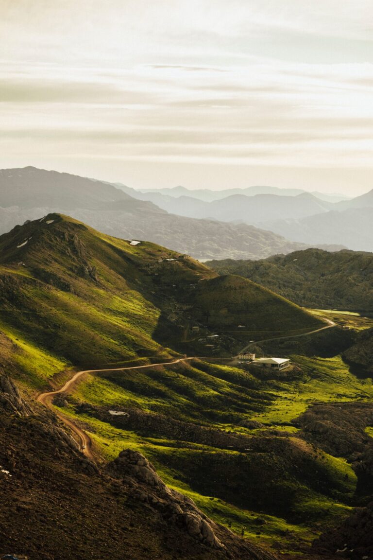 Solitary path winding through gentle mountain slopes at dusk